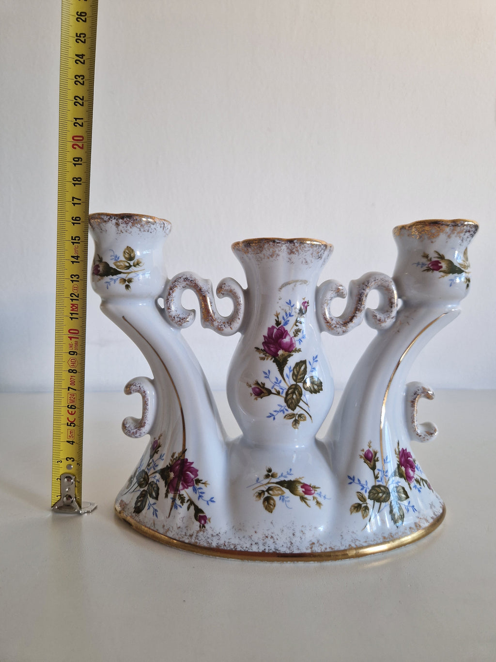 Vintage white porcelain three-arm candelabra with floral rose patterns and gold trim.