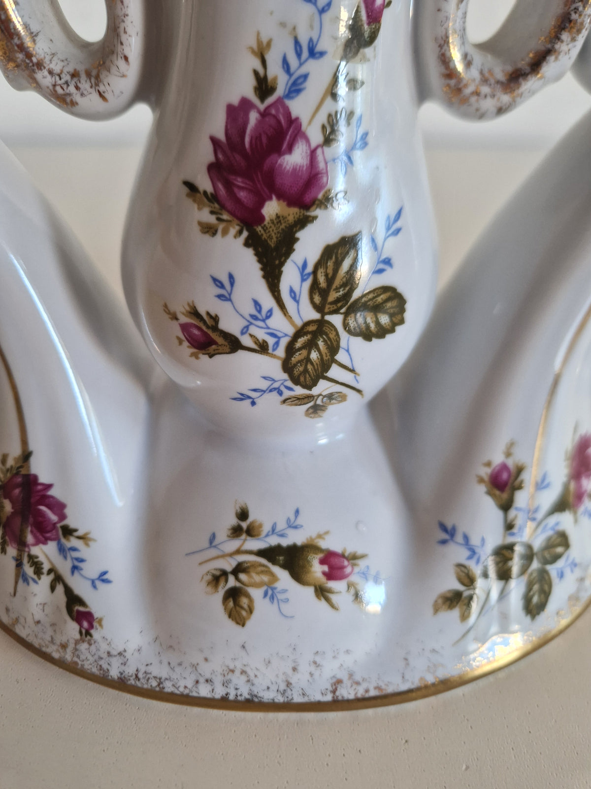 Vintage white porcelain vase with pink rose floral pattern and gold rim accents.