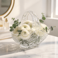 Vintage cut crystal basket filled with white ranunculus and eucalyptus leaves on a marble surface