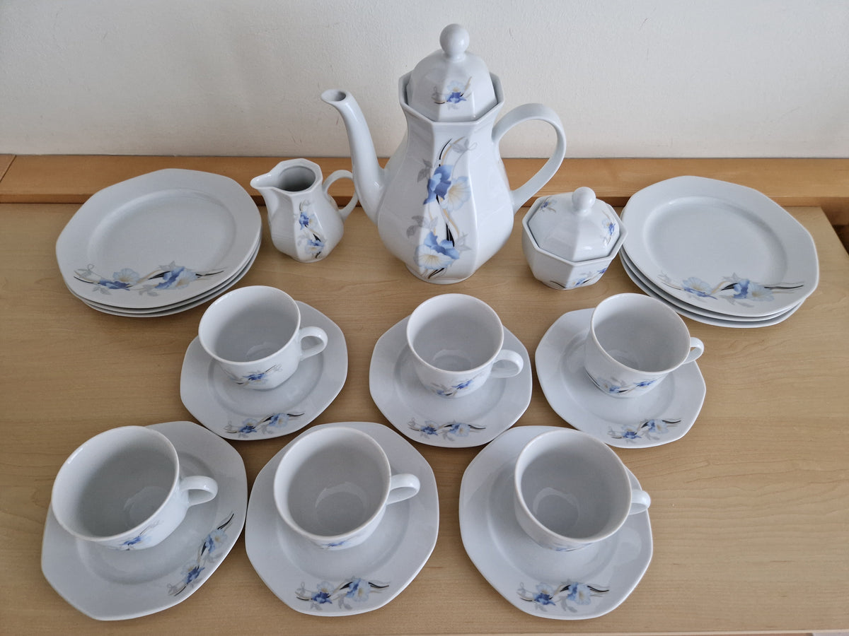 Vintage white porcelain tea set with blue floral pattern including teapot and cups.