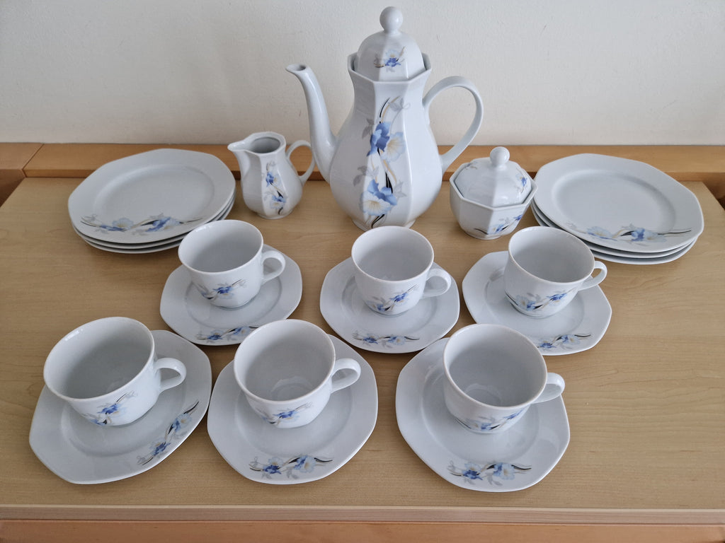 Vintage white porcelain tea set with blue floral pattern including teapot, cups, and plates.