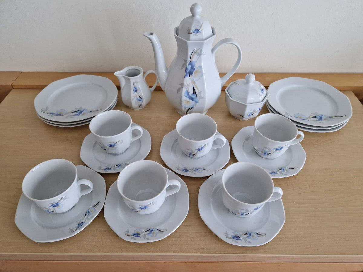 Vintage white porcelain tea set with blue floral pattern including teapot, cups, and plates.