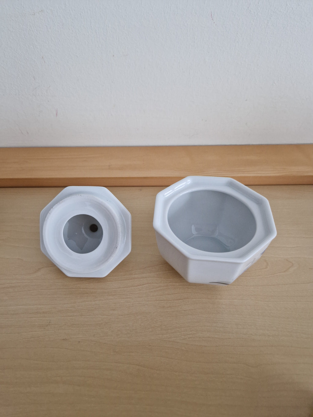 Vintage white porcelain octagonal jar and matching lid on a wooden surface