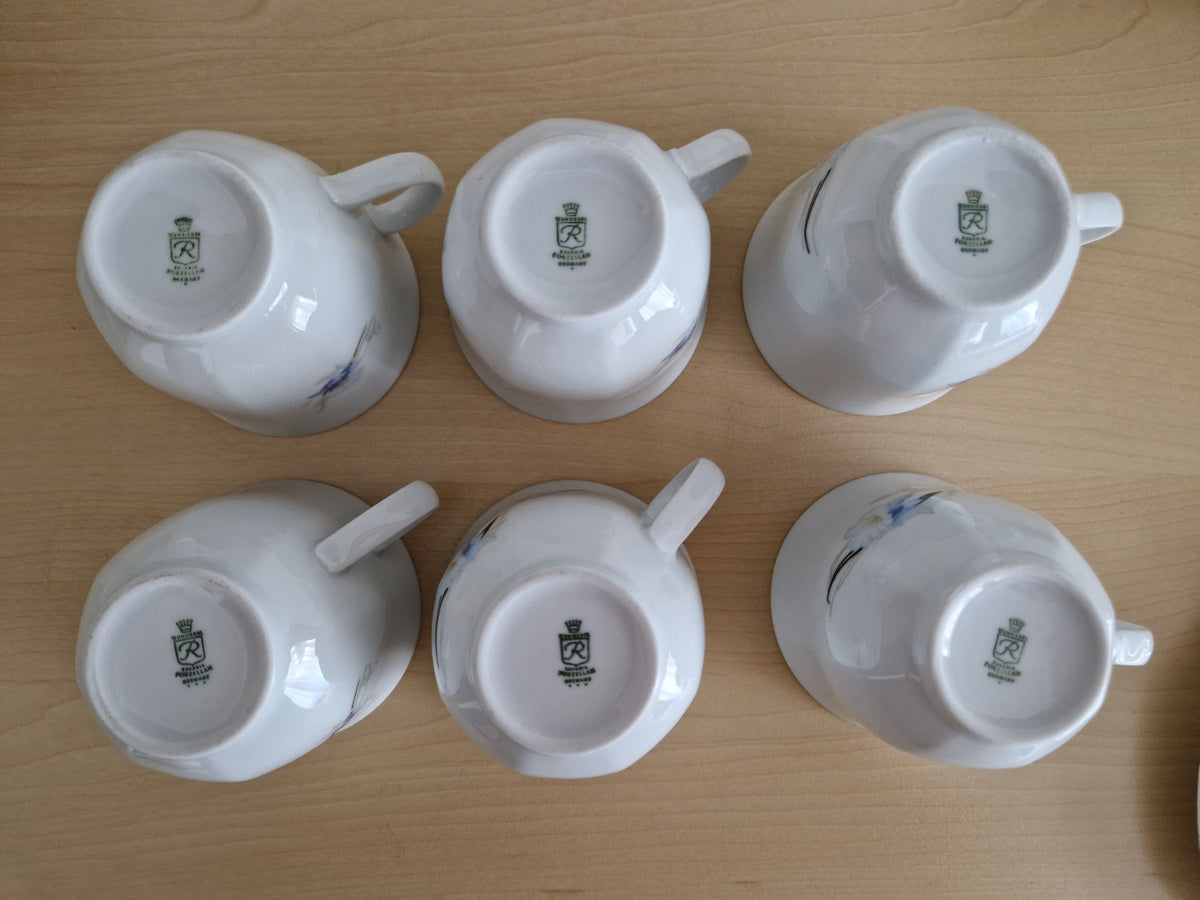 Set of six vintage white porcelain teacups with blue floral patterns, shown upside down.