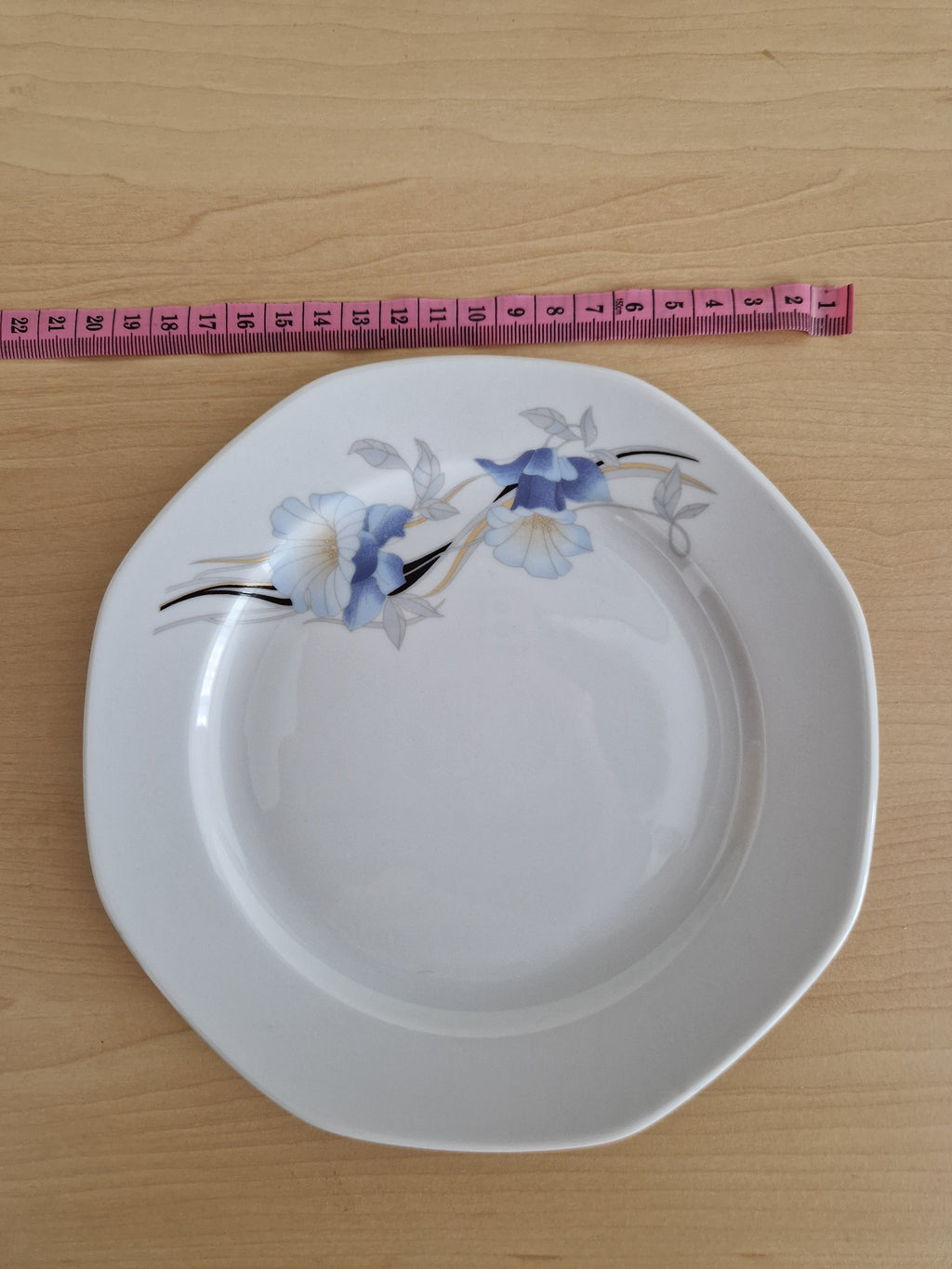 Vintage white porcelain plate with blue floral pattern and a pink measuring tape.
