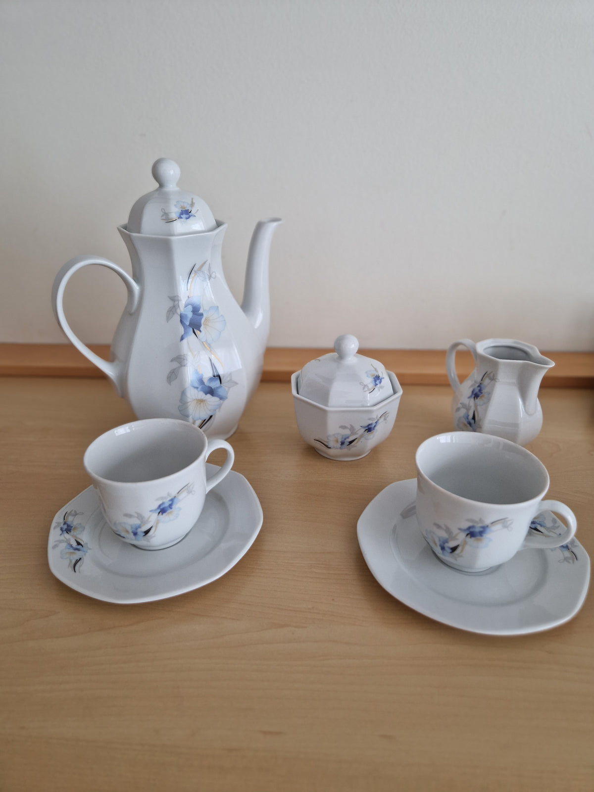 Vintage white porcelain tea set with blue floral pattern, including teapot, cups, and sugar bowl