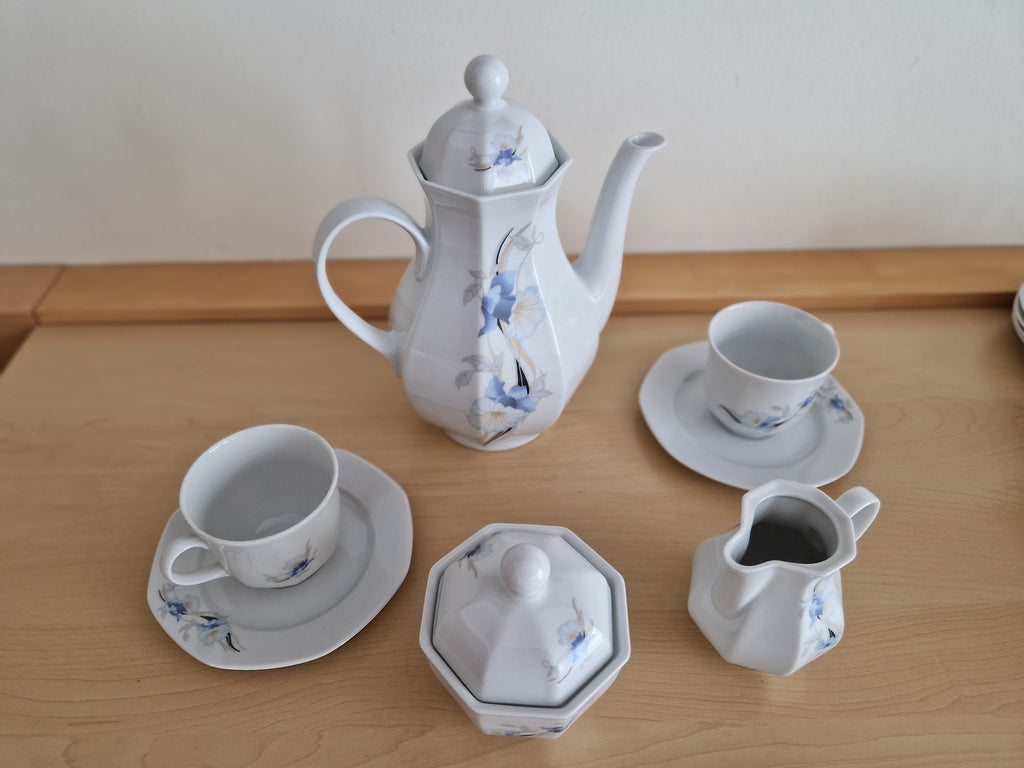 Vintage white porcelain tea set with delicate blue floral patterns and matching cups.