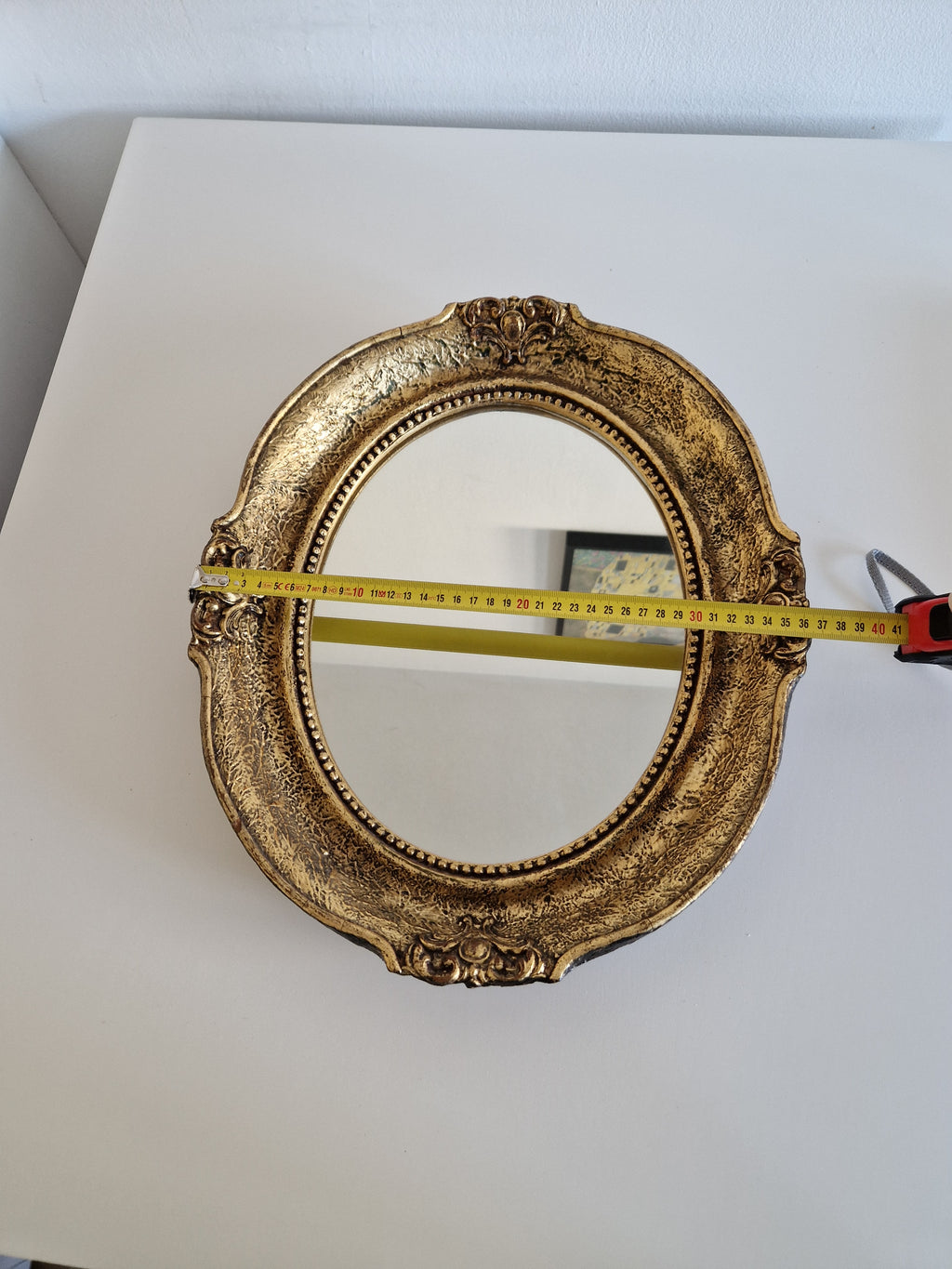 Baroque oval gilt mirror measured at approximately 41 cm wide, showing beaded inner border and cartouche accents