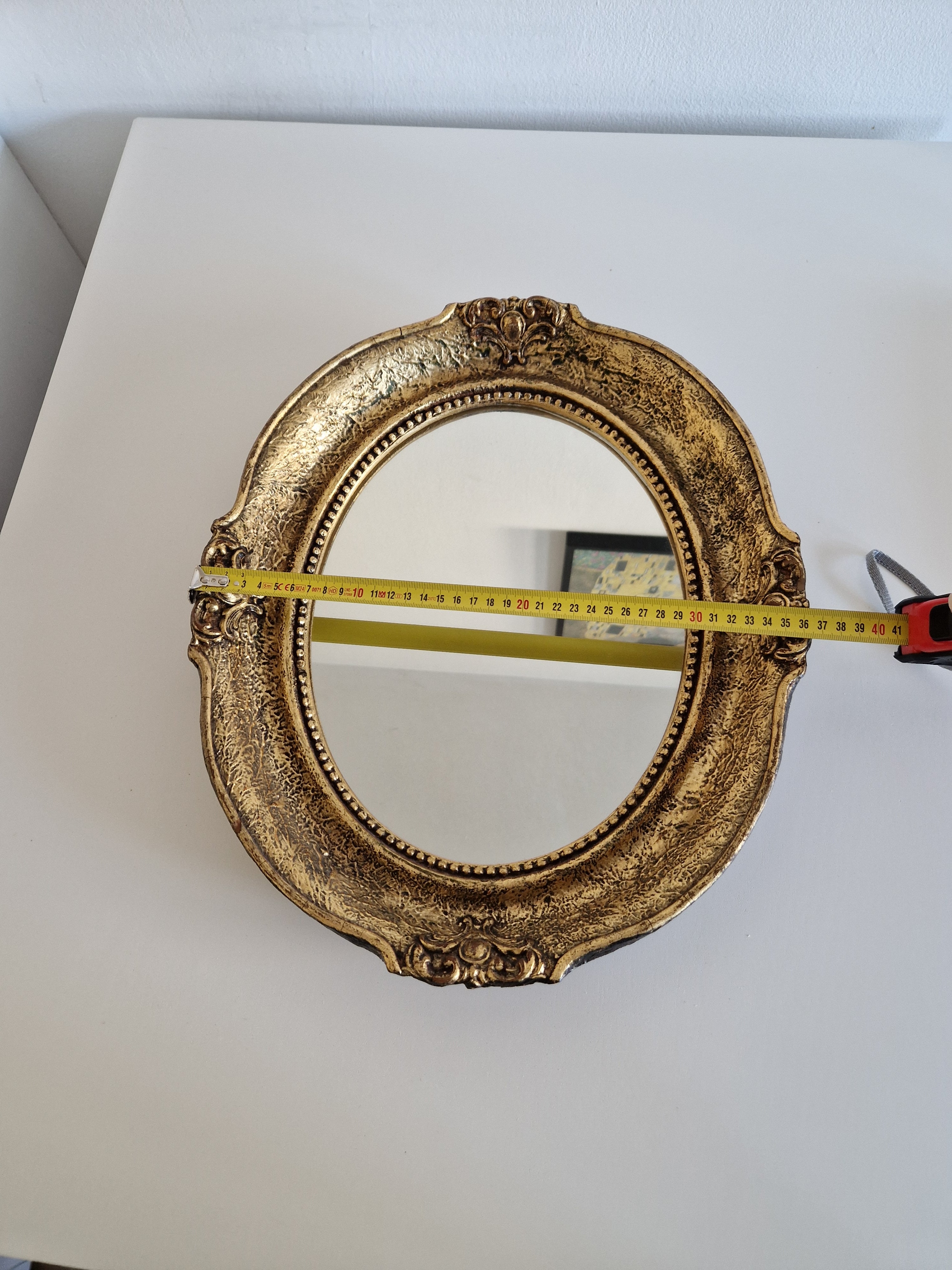 Baroque oval gilt mirror measured at approximately 41 cm wide, showing beaded inner border and cartouche accents