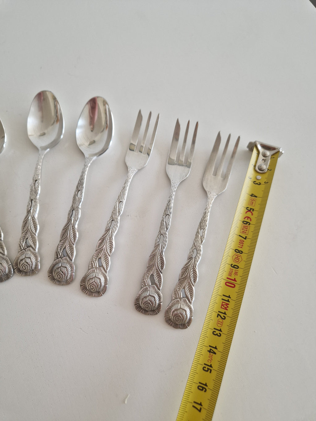 All 14 pieces laid out — tea spoons and cake forks with rose-embossed handles