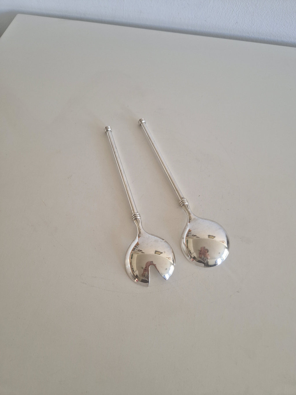 Close-up of WMF silver-plated salad server bowls showing open slot fork design and mirror finish