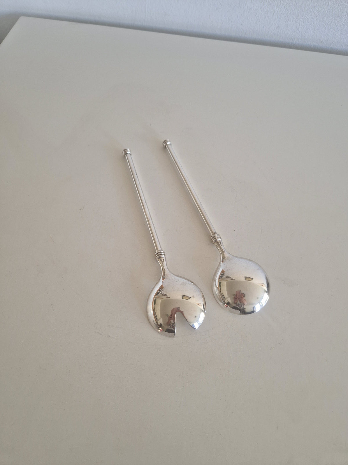 Close-up of WMF silver-plated salad server bowls showing open slot fork design and mirror finish