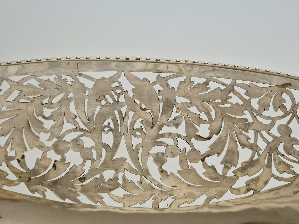 Close-up of hand-pierced reticulated wall showing copper base metal visible through worn silver plate