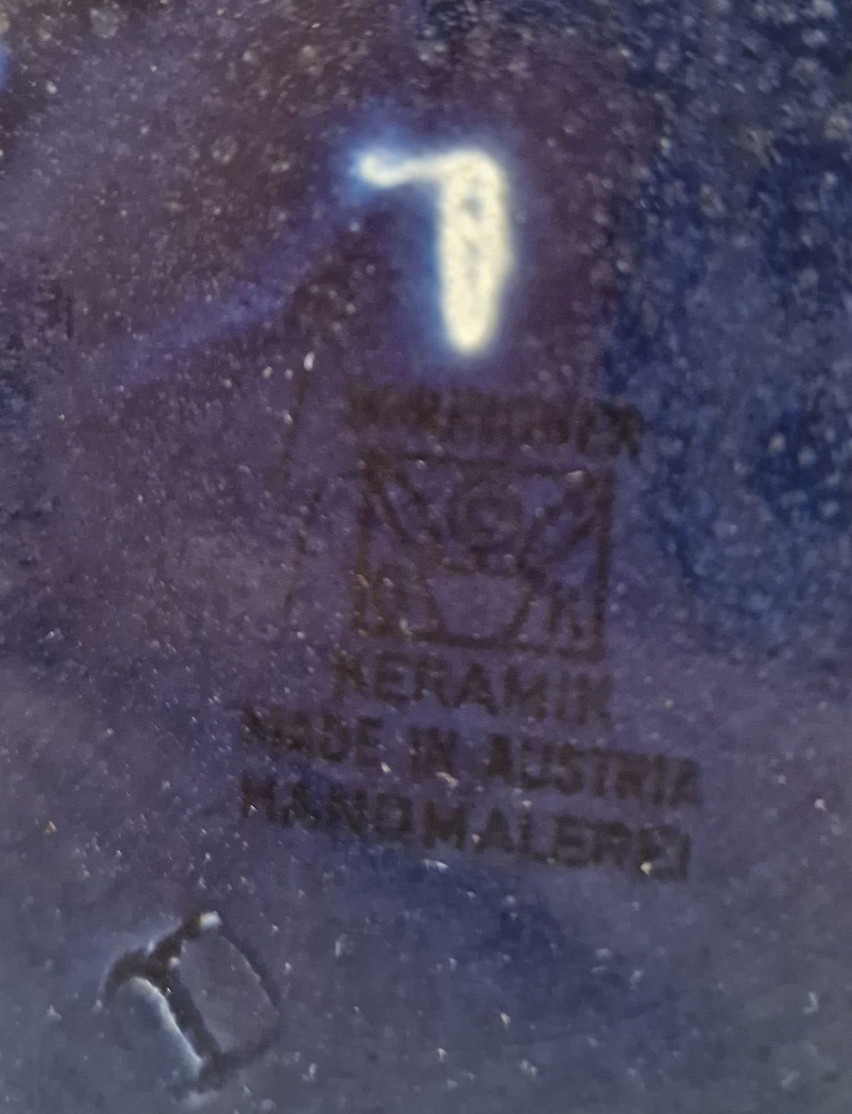Close-up of a blue ceramic maker's mark stamp reading Keramik Made in Austria Handmalerei.