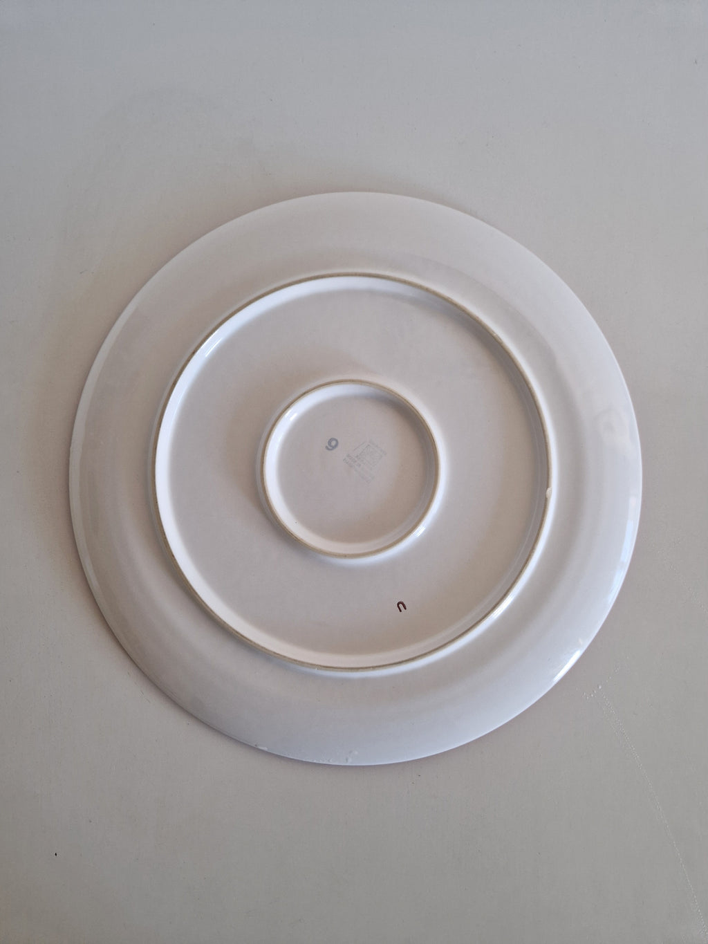 Bottom view of a white vintage porcelain plate on a plain background