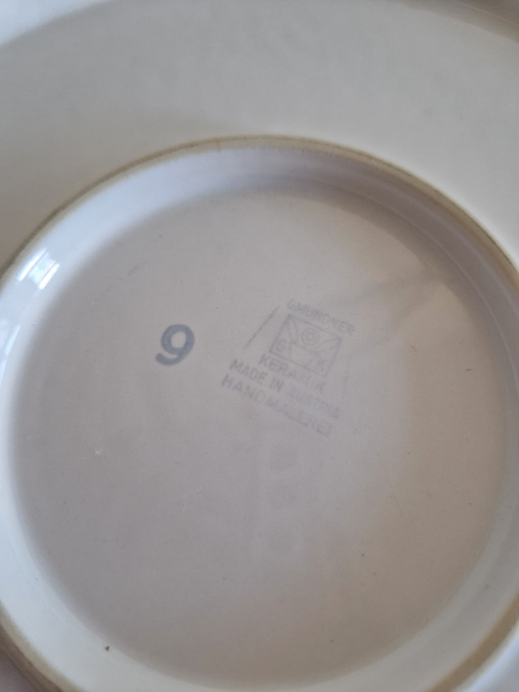 Close-up of the bottom of a white porcelain plate with Gmundner Keramik Made in Austria stamp
