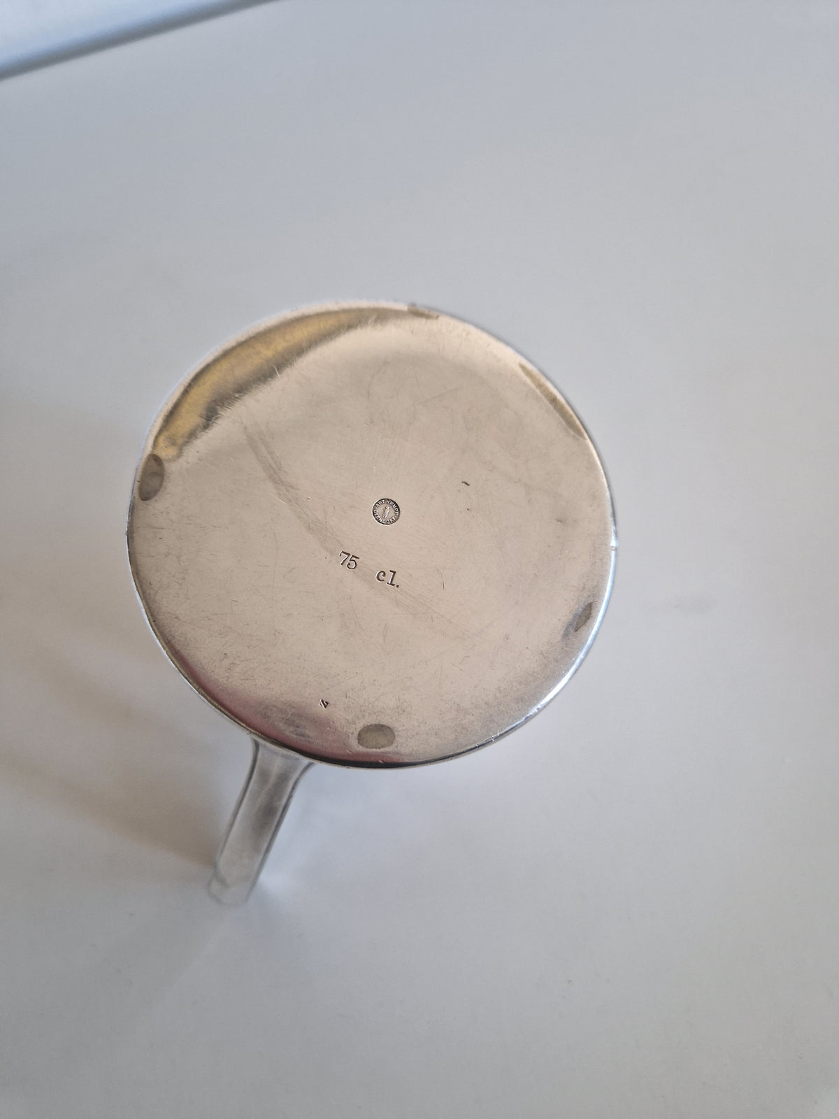 Bottom view of a vintage silver cup showing 75 cl capacity engraving.