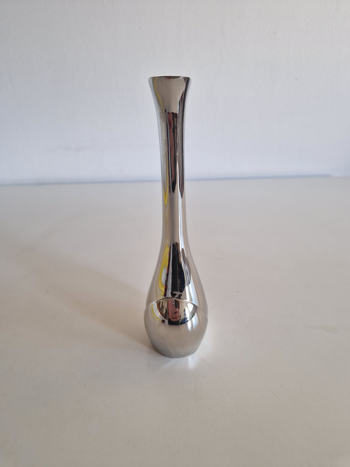 Minimalist polished silver metal bud vase with a slender neck and rounded base