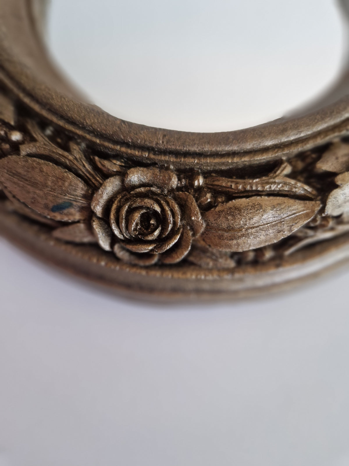 Close-up of a vintage carved wooden frame featuring intricate rose and leaf floral details.