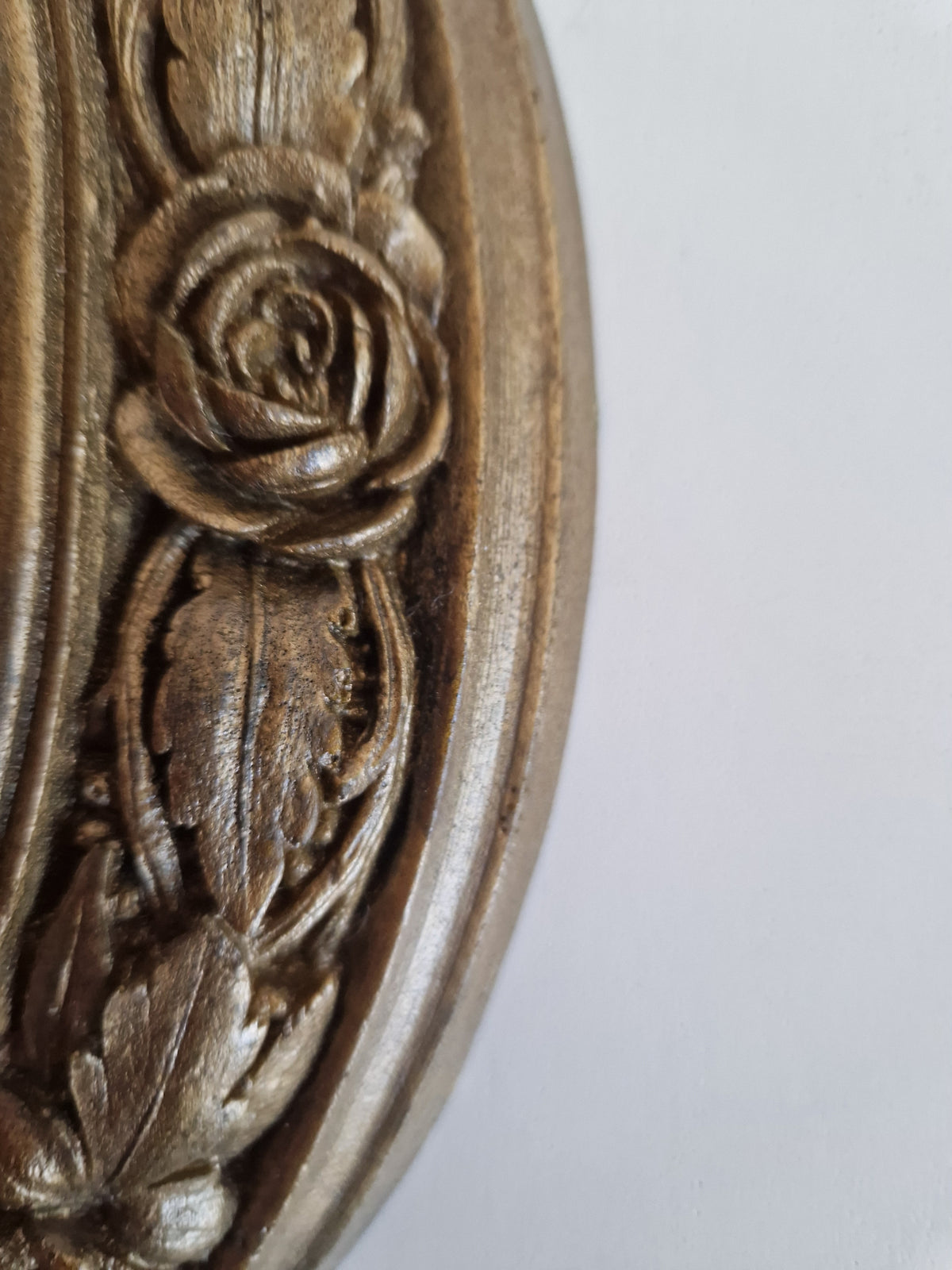 Detailed gold-toned vintage carved floral relief with rose and leaf patterns.