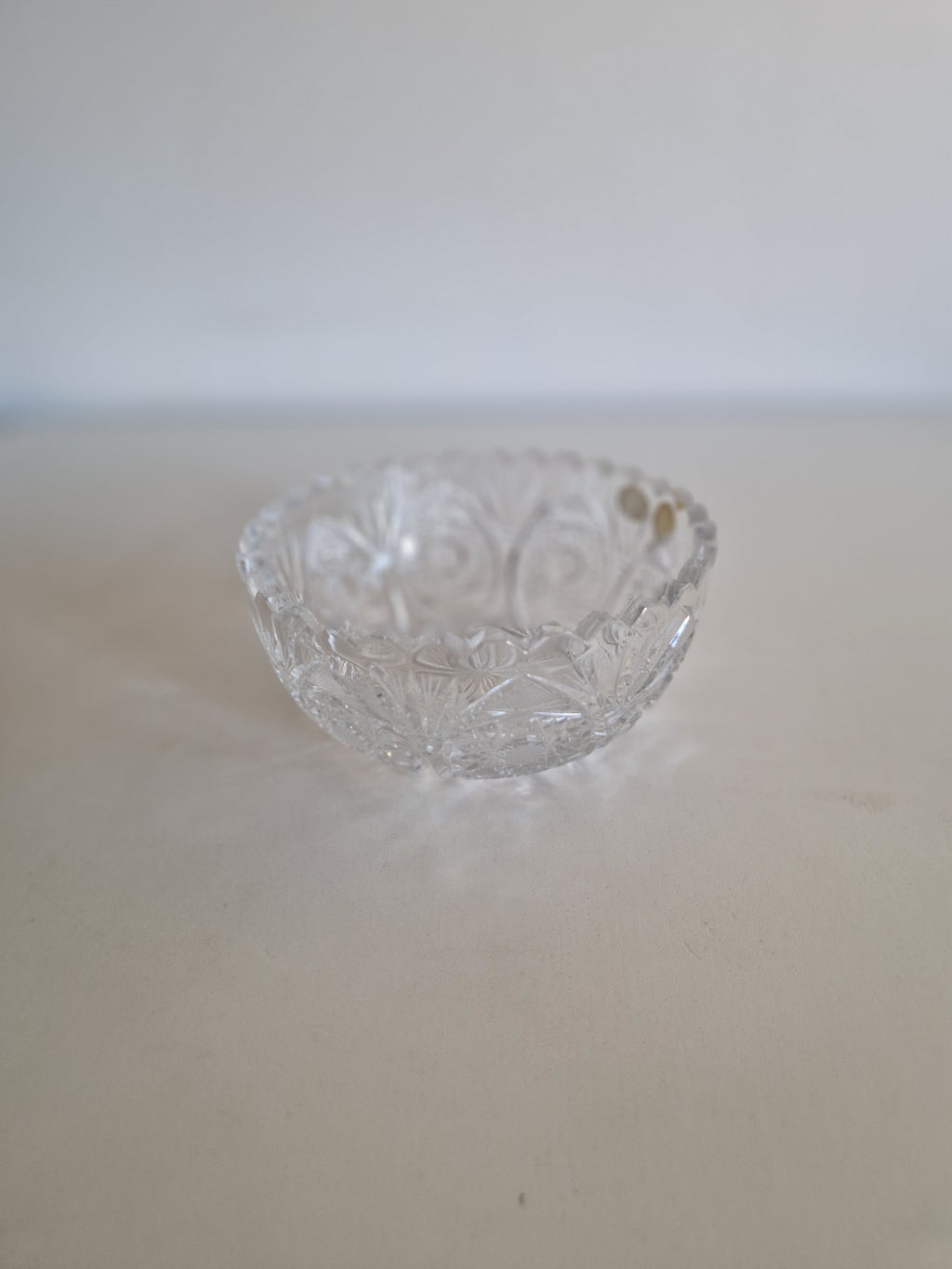 Vintage cut crystal glass bowl with intricate decorative patterns on a white surface.