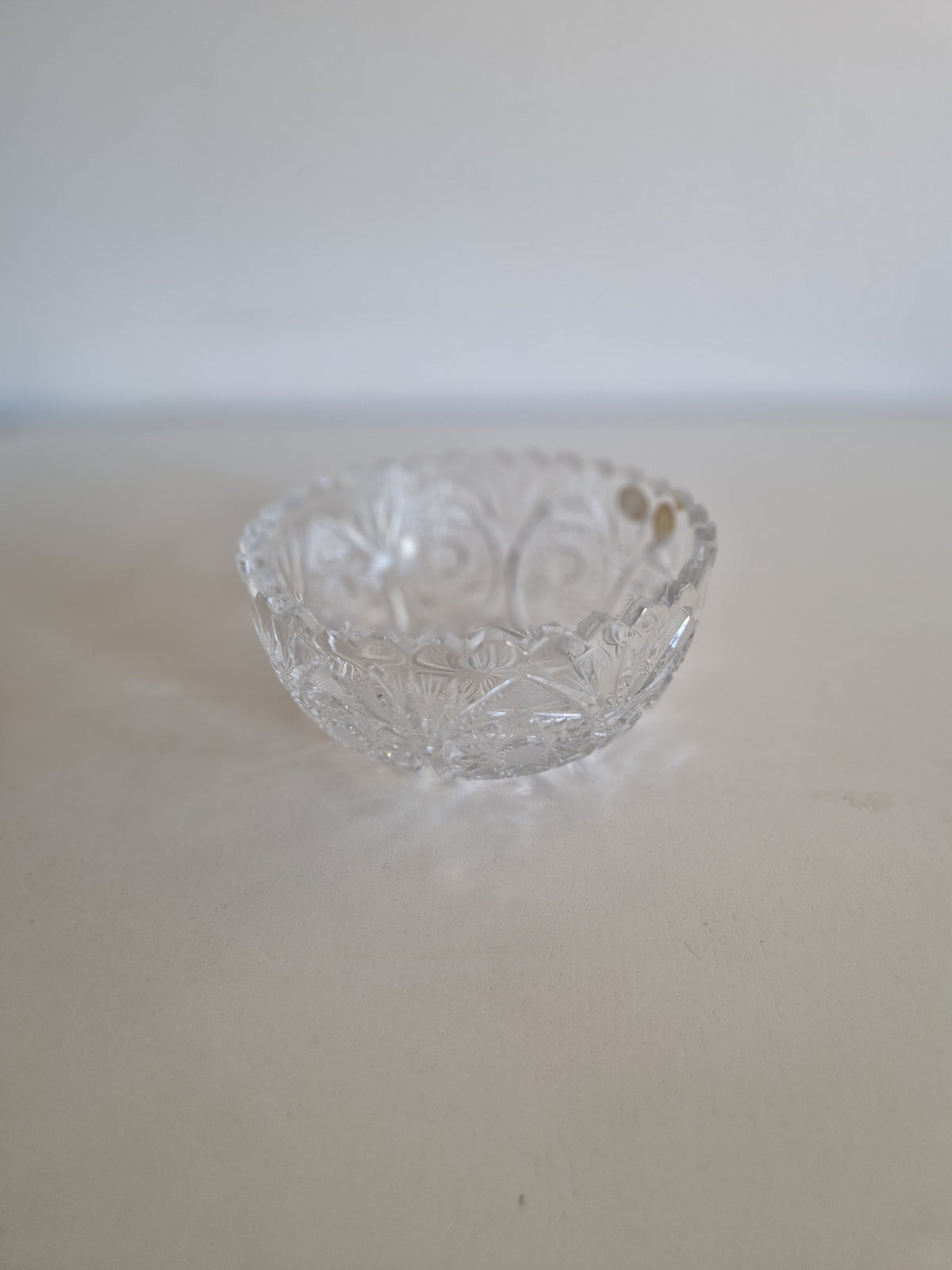 Vintage cut crystal glass bowl with intricate decorative patterns on a white surface.
