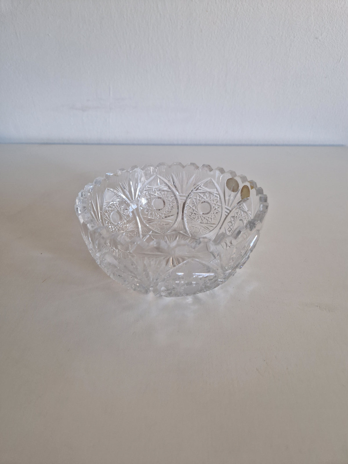 Vintage cut crystal glass bowl with intricate geometric patterns and scalloped rim.