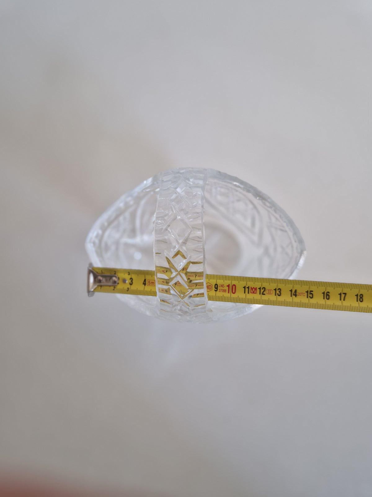 Vintage cut crystal glass basket with a yellow measuring tape across the center