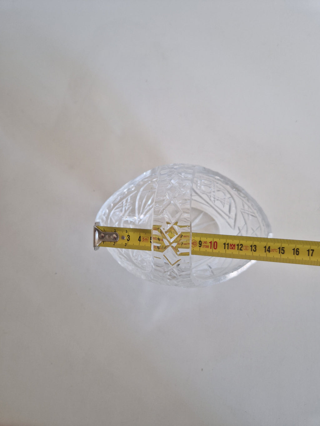 Vintage cut glass decorative bowl with a measuring tape showing its size.